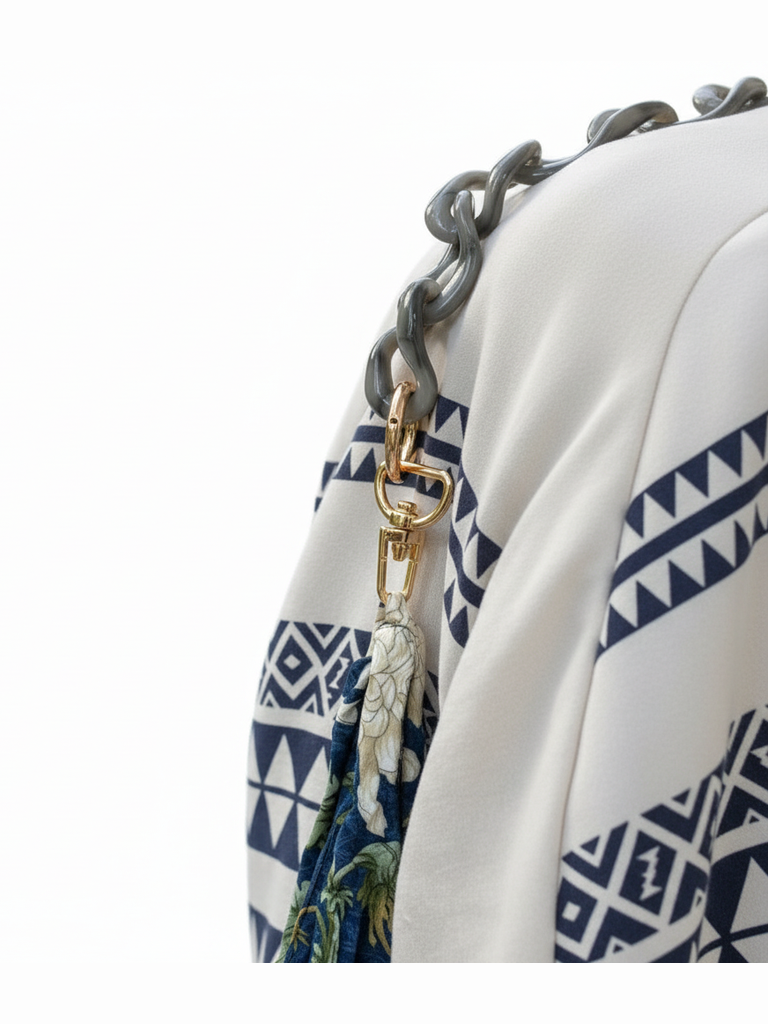 Be Bougie grey acrylic chain bag strap with gold-tone clasp attached to a patterned white and blue tote bag