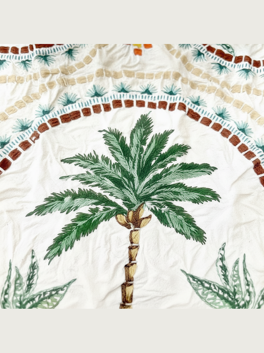 Be Bougie eco bag featuring a detailed palm tree mosaic print in green, brown, and cream on stretchy crinkled fabric.
