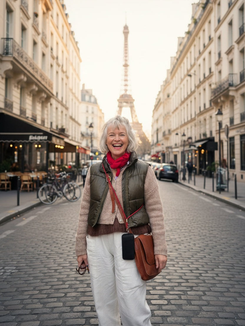 Be Bougie red sparkly cross body phone strap worn by a smiling woman on a cobblestone street in Paris