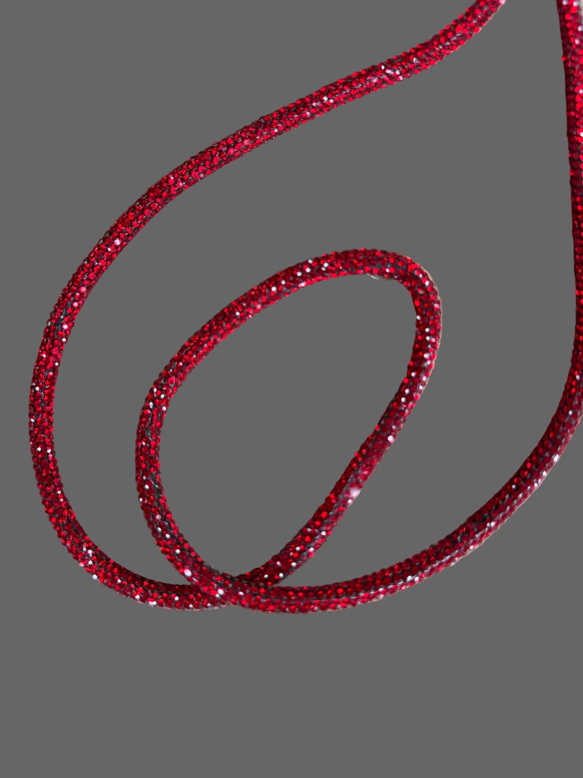 Be Bougie red sparkly cross body phone strap with a glittery textured finish for hands-free phone carrying.