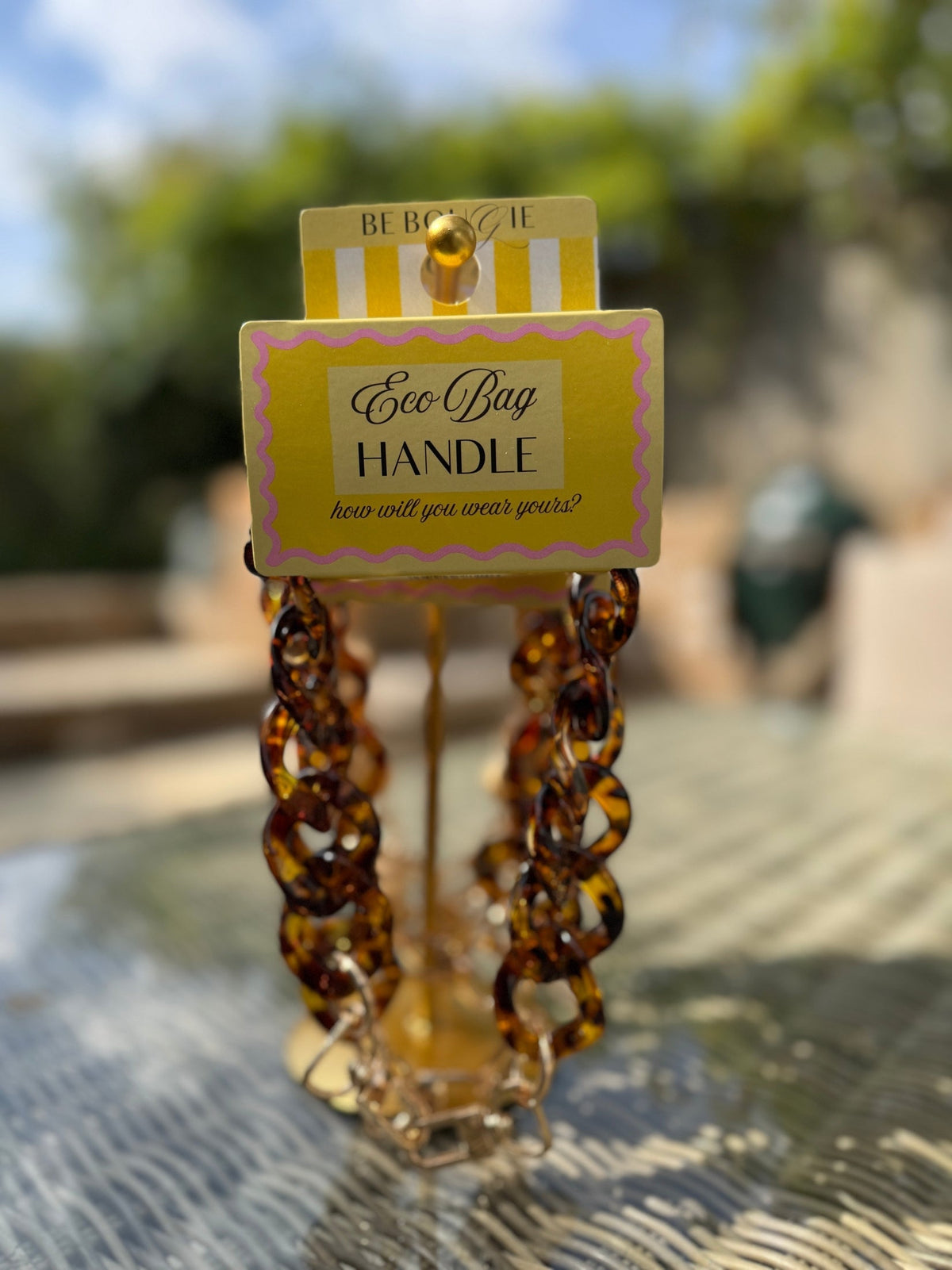 Be Bougie tortoiseshell chain link bag handle accessory with gold hardware on branded yellow display card